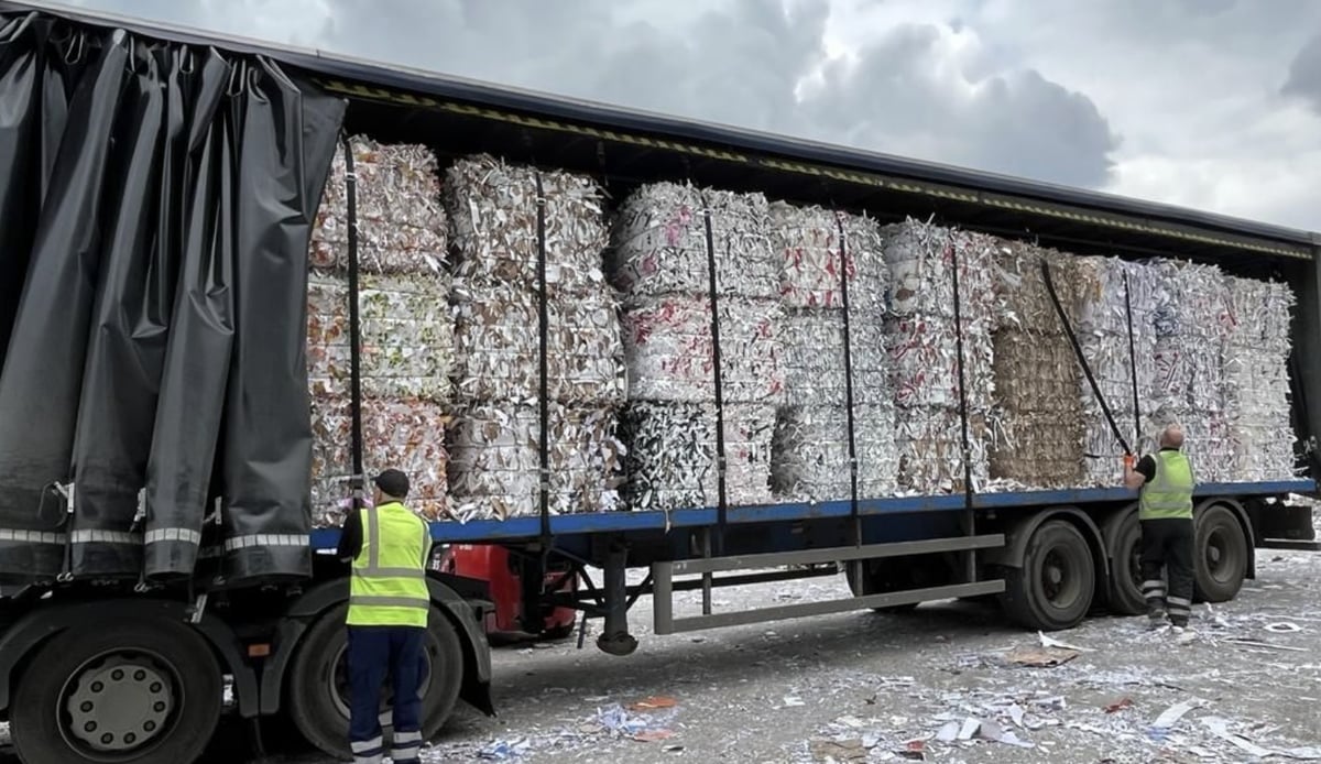 Two Pulp Friction staff in hi-vis loading a curtainside trailer stacked with bales of paper