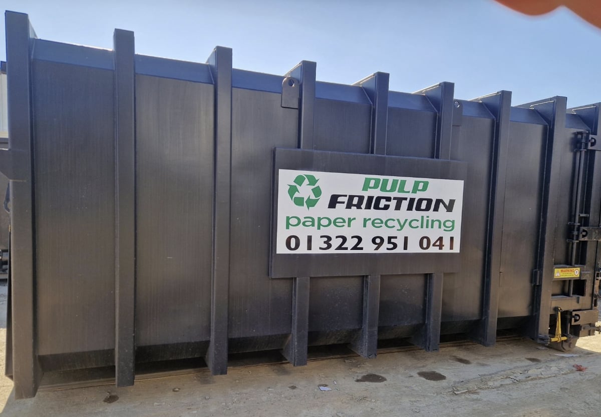 Black Pulp Friction branded compactor container in the yard