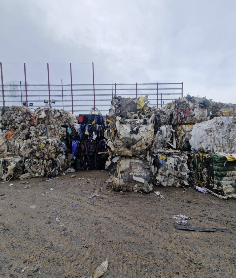 Mixed bales of paper, card and plastic in the yard under a grey sky
